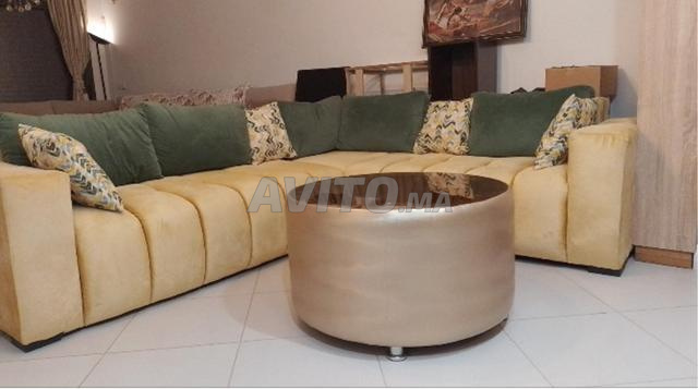 Canapé en L en bon état avec oreillers et table. 