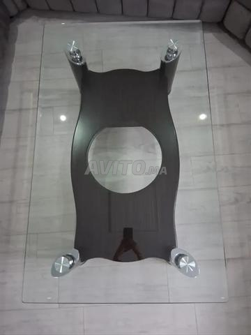 طاولة أنيقة بسطح زجاجي وقاعدة خشبية.