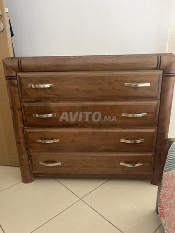Un lit en bon état avec tables de nuit et commode